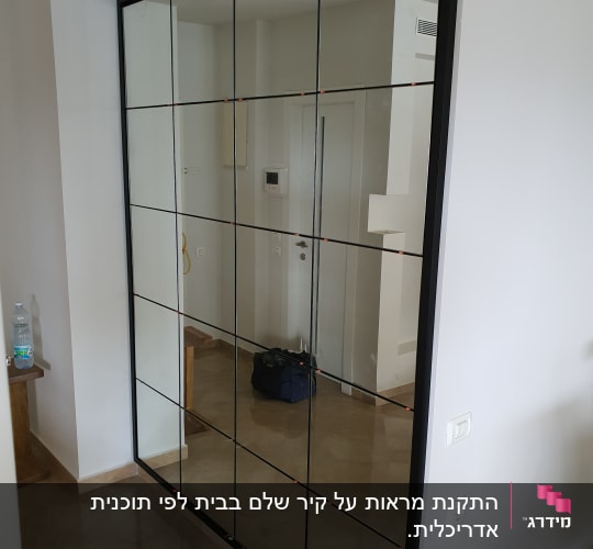 מראה גדולה עם מסגרת שחורה על קיר לבן